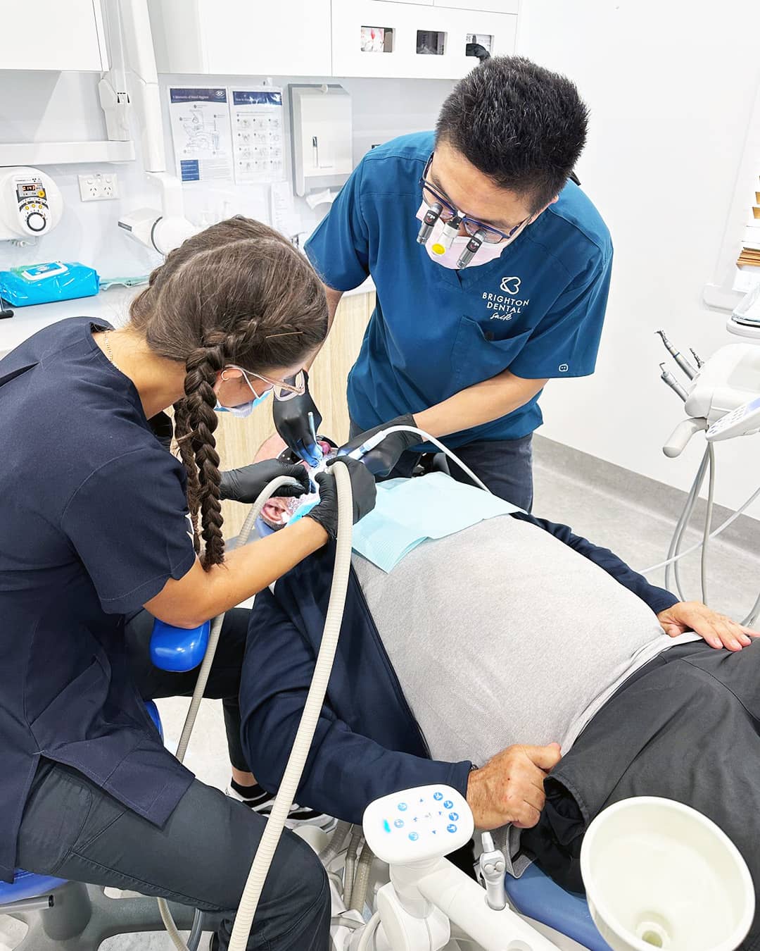 Dr. Ken providing clinical dental care at Beyond Dental Care Brighton, supported by a dental assistant during patient treatment