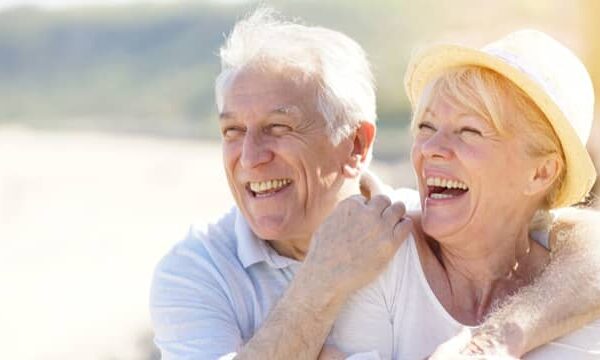 A smiling couple enjoys a sailing trip, showcasing the positive impact of dental bridges on their ability to eat, speak, and smile with confidence.