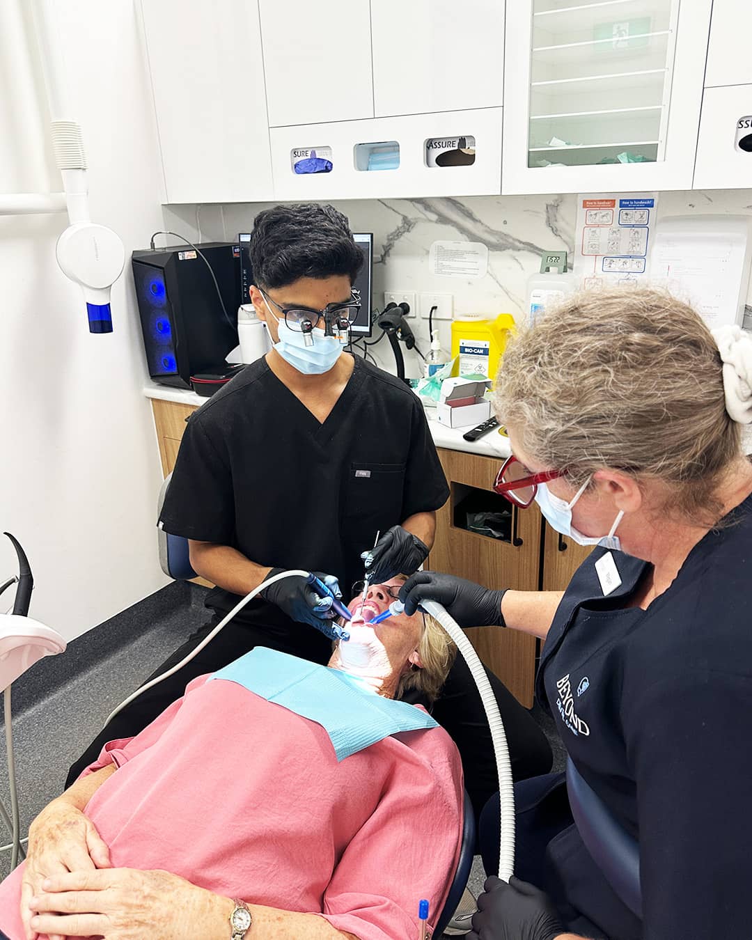 Dr. Eshaan performing a dental procedure at Beyond Dental Care Sandstone Point, assisted by a team member