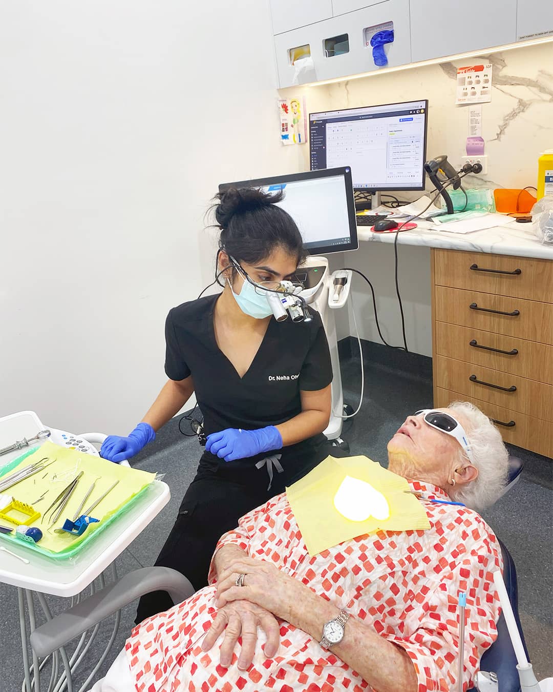Dr. Neha Ohri consulting with an elderly patient before treatment in a modern dental room