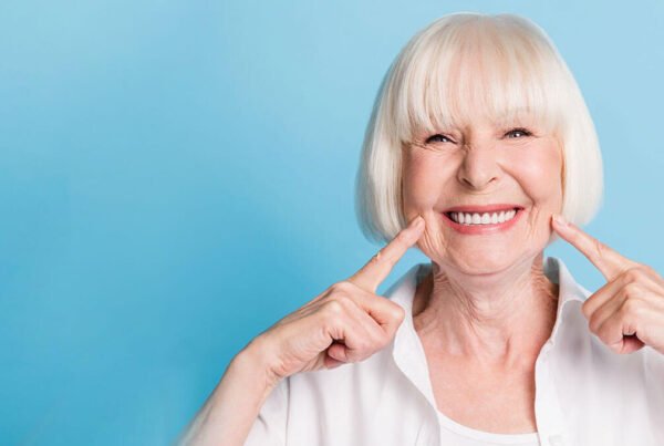 Happy senior patient pointing at teeth