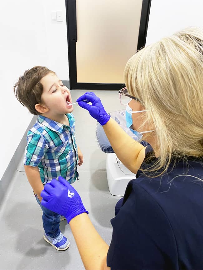 A Beyond Dental Care team member applies topical fluoride to a boy's teeth, protecting his smile and preventing cavities.