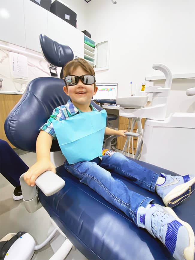 A young boy enjoys a fun and engaging first dental visit at Beyond Dental Care, sporting cool sunglasses and feeling at ease with the friendly staff.