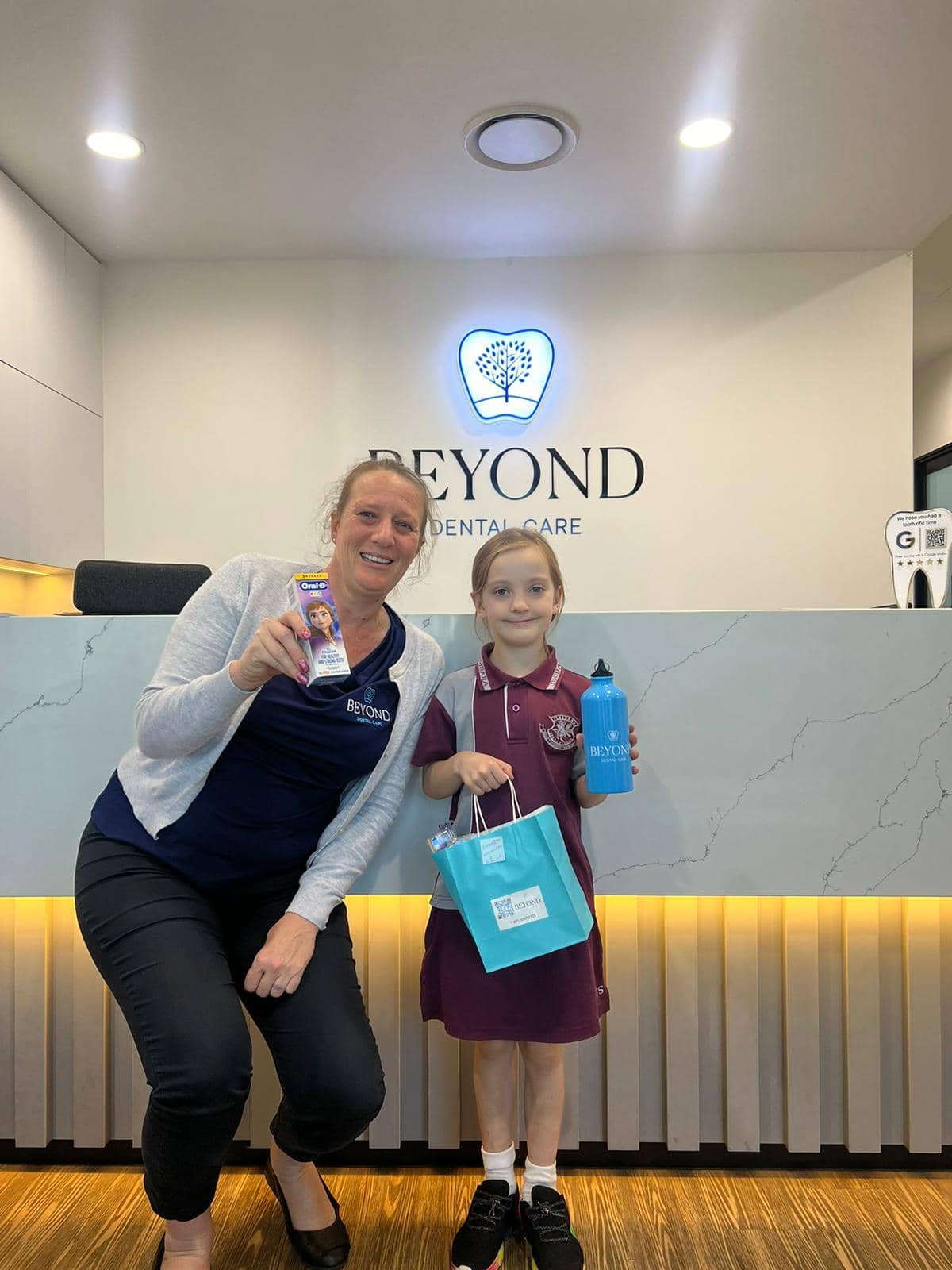 Practice manager Brooke Lilley with a child patient and dental care gift bag at Beyond Dental Care Burpengary