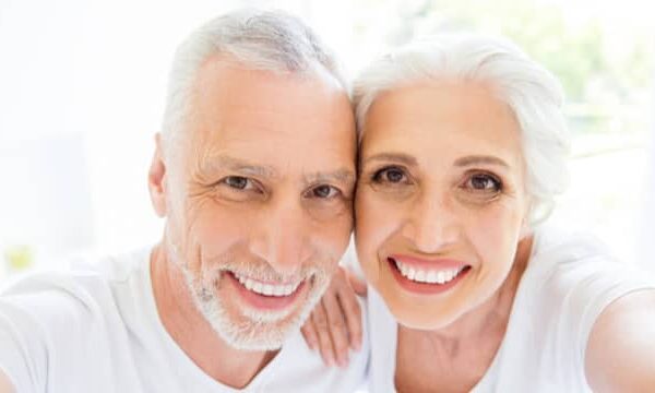 Smiling senior couple wearing dentures, showing the confidence and happiness that come with a healthy smile.