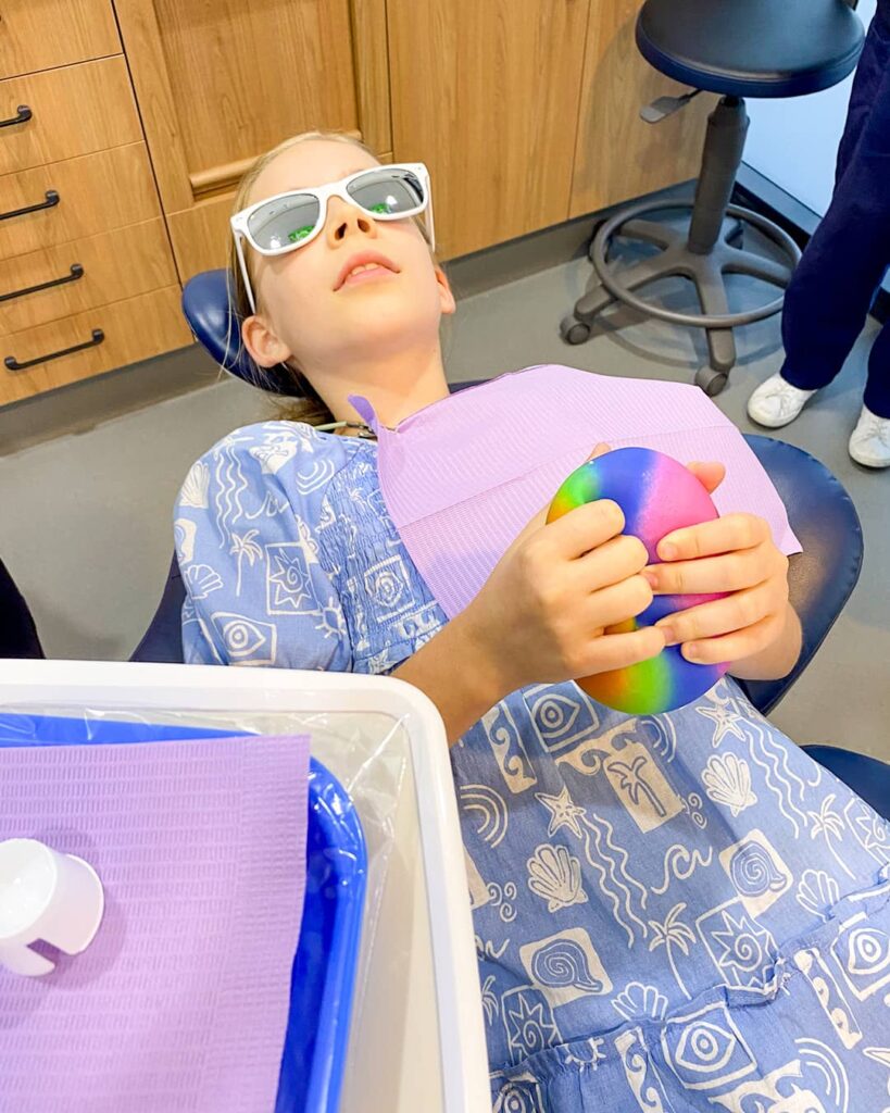 Young Patient Squeezing Stress Ball A young patient in a dental chair holding a rainbow stress ball